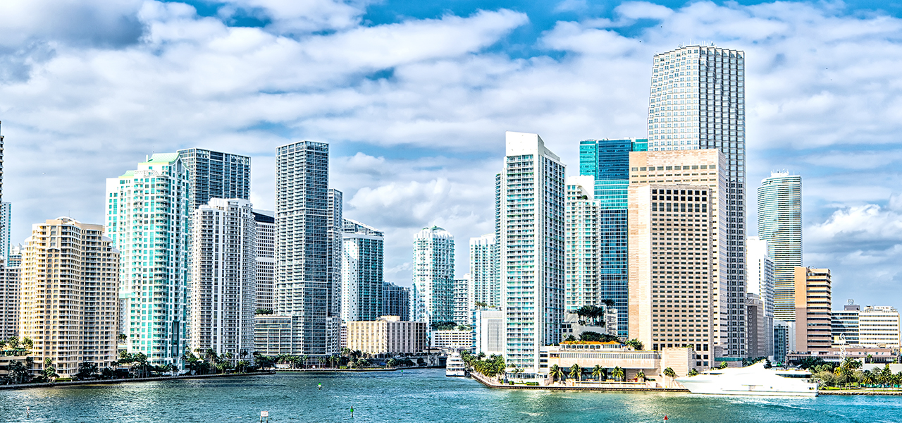 Miami skyline of waterfront high-rises under a partly cloudy sky