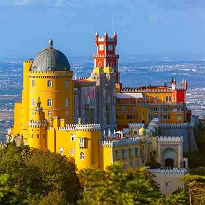 Colorful yellow and red hilltop palace with towers and domes in Sintra, Portugal