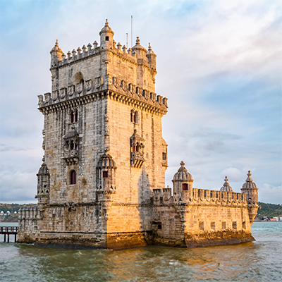 Belém Tower, an ornate stone fortress standing in the water near Lisbon, under a cloudy sky