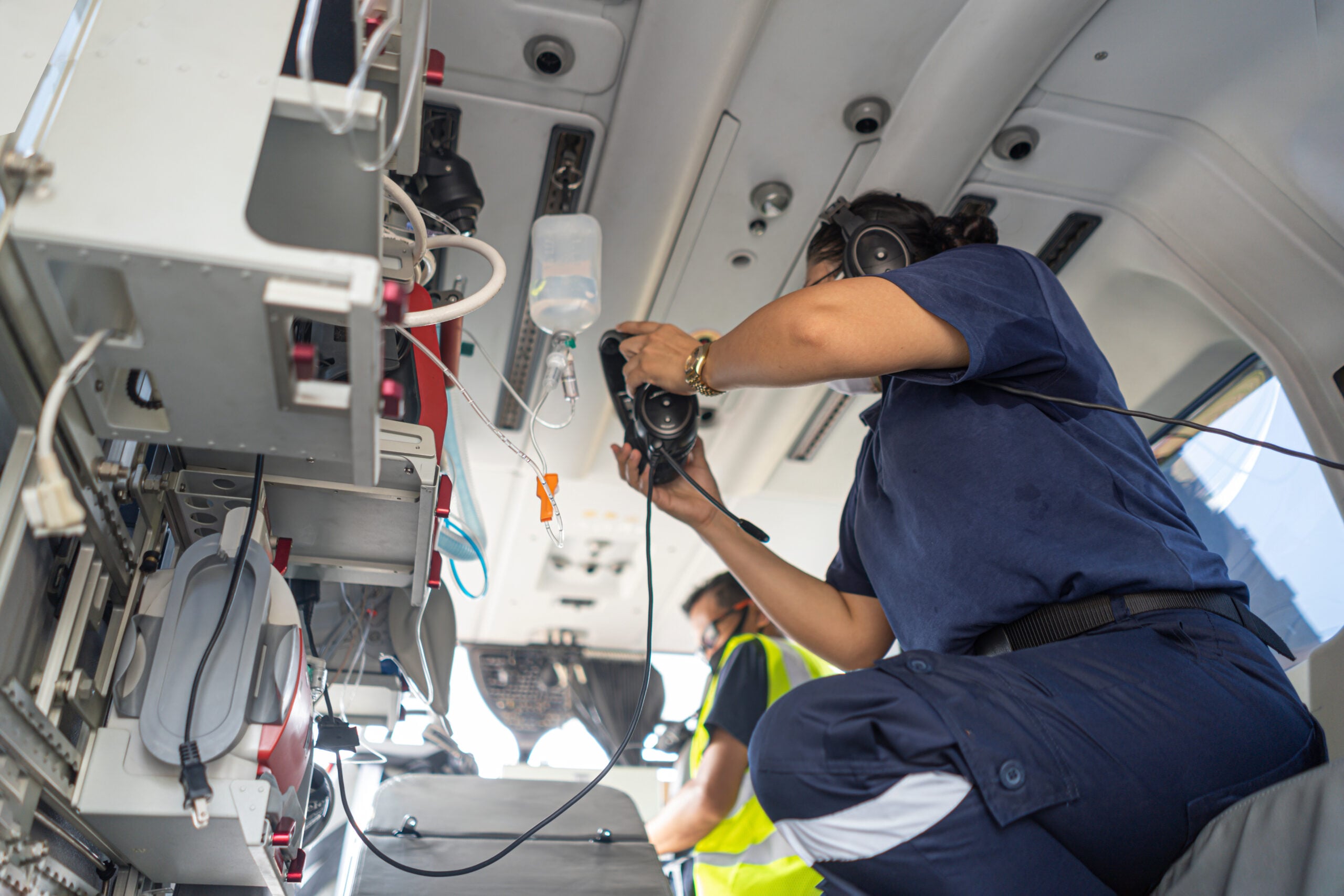 Flight nurse tending to medical equipment aboard an air ambulance cabin